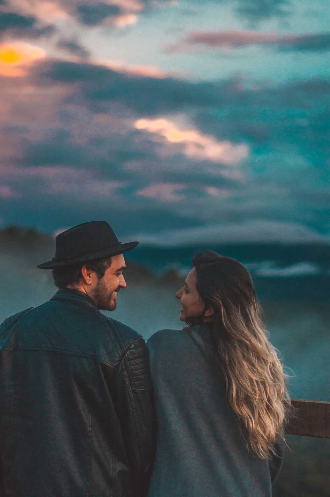 Pareja mirándose bajo un cielo crepuscular