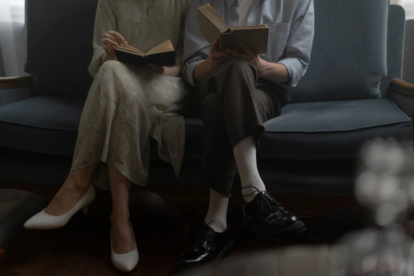 Dos personas leyendo un libro en un sofá, ambiente cálido y elegante