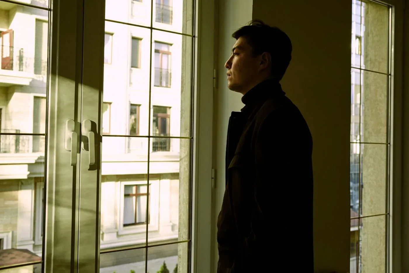 Hombre solo mirando por la ventana, pensativo