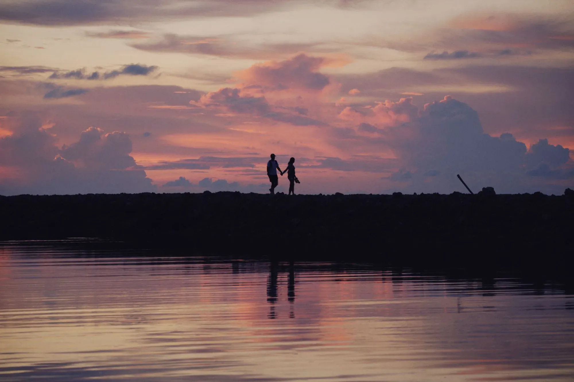 Pareja abrazada en silueta frente a un atardecer