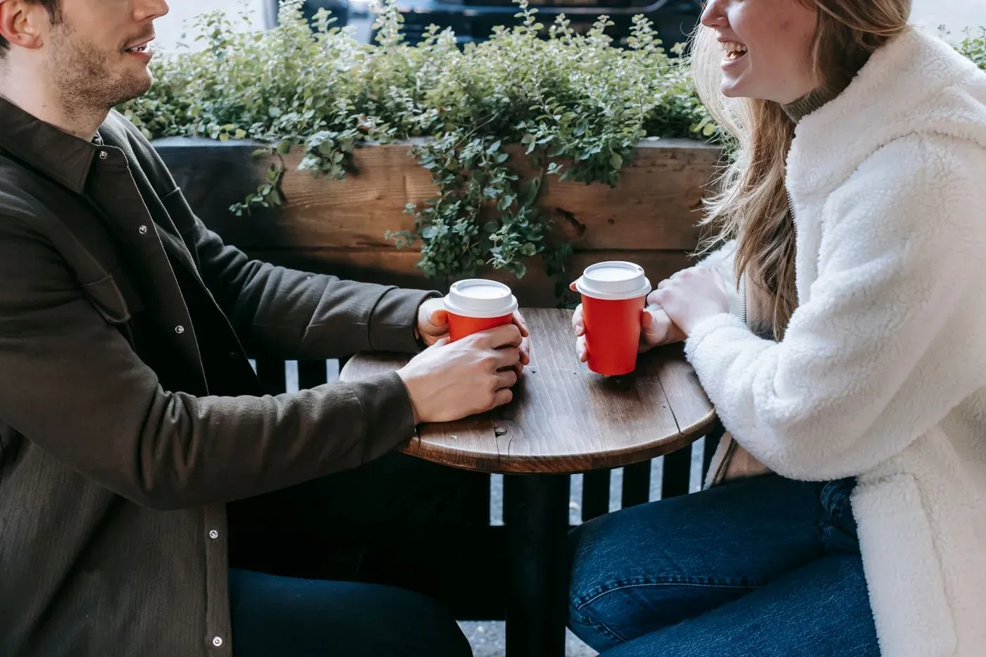 Pareja conversando con un café entre las manos