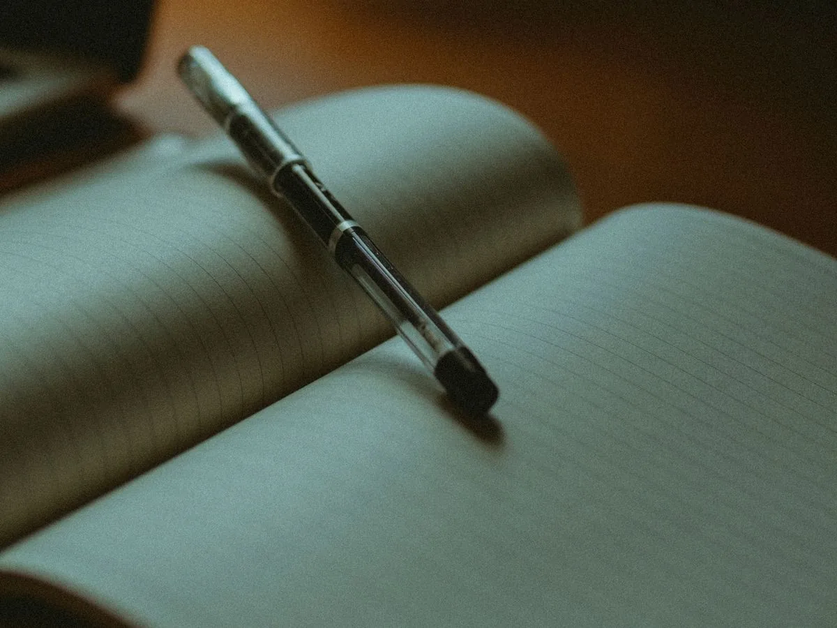 Un bolígrafo sobre un cuaderno abierto con las páginas en blanco