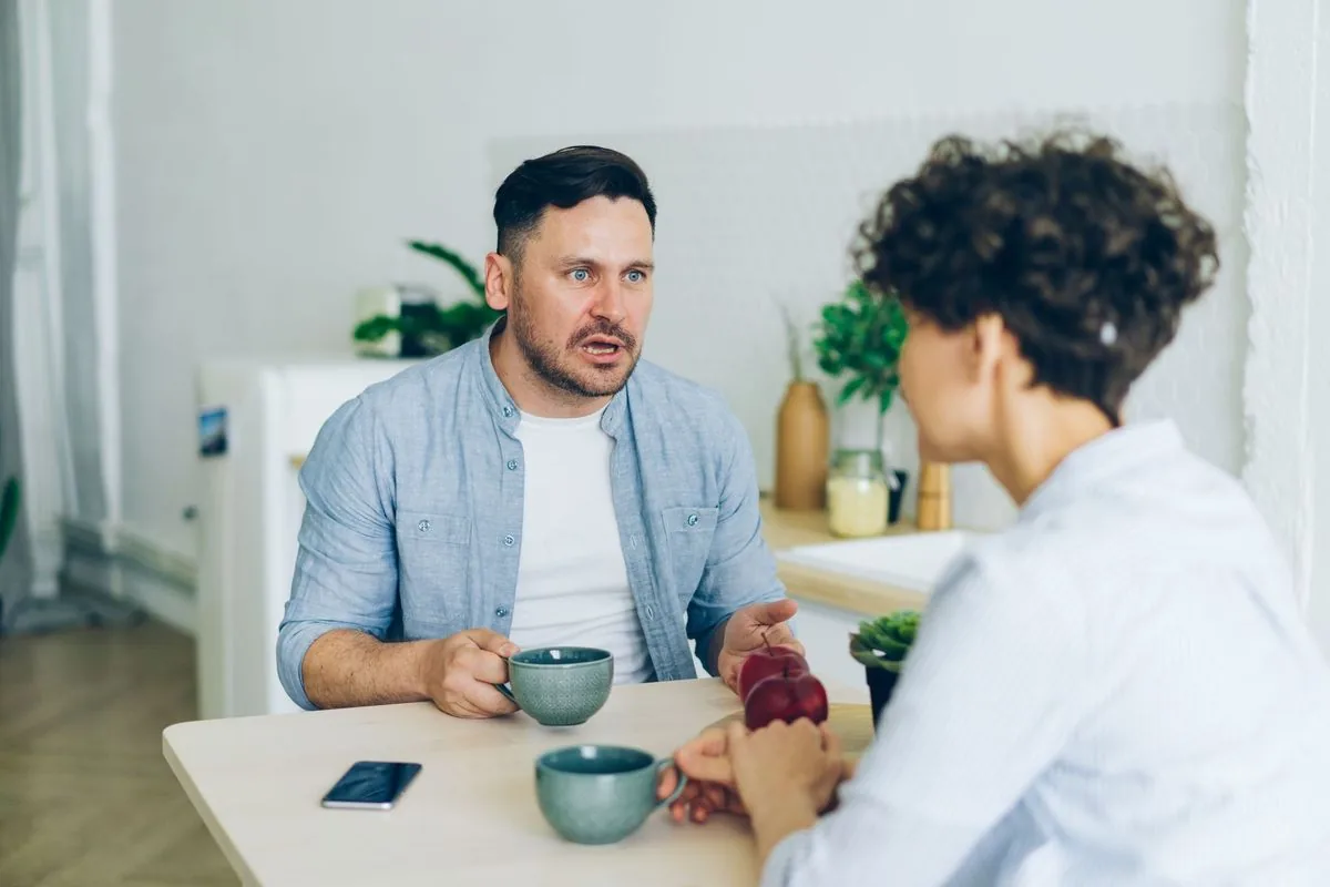 Pareja conversando con calma en la mesa de la cocina, con dos tazas de café