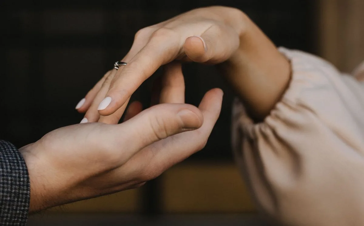 Las manos de una pareja acercándose con delicadeza hasta tocarse