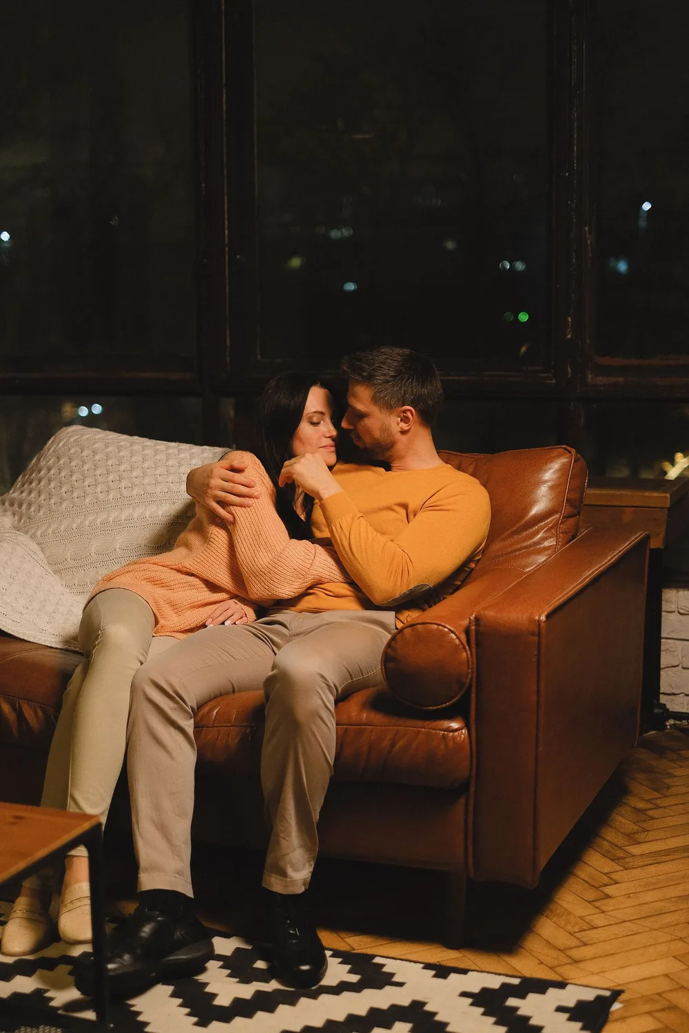 Pareja abrazada en el sofá de noche, con los ojos cerrados