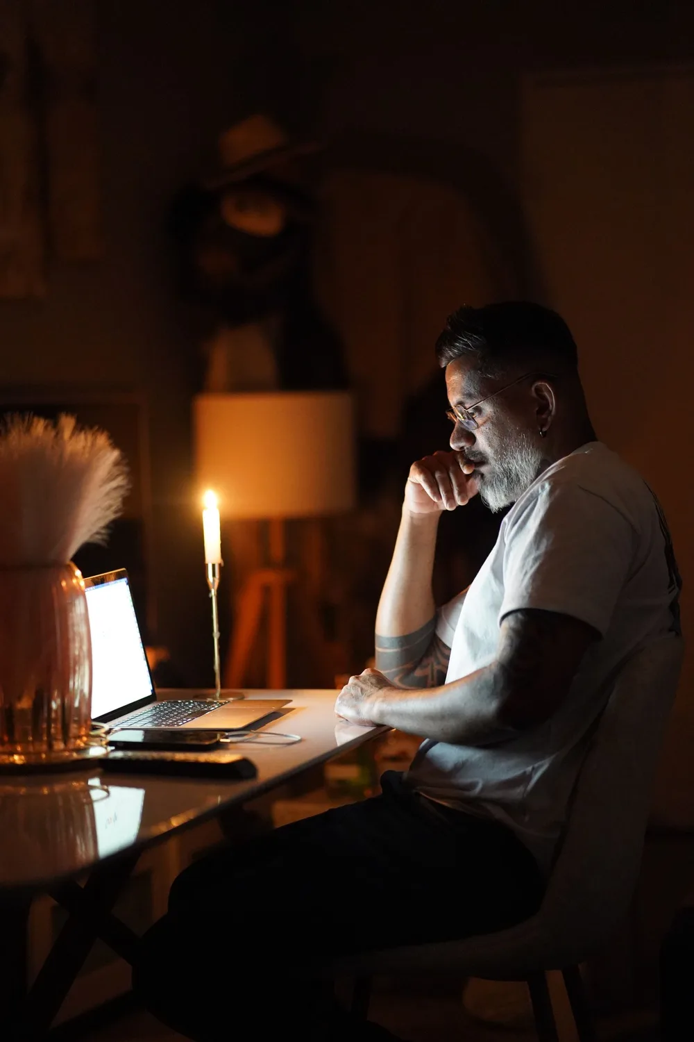 Hombre trabajando de noche en su laptop a la luz de una vela
