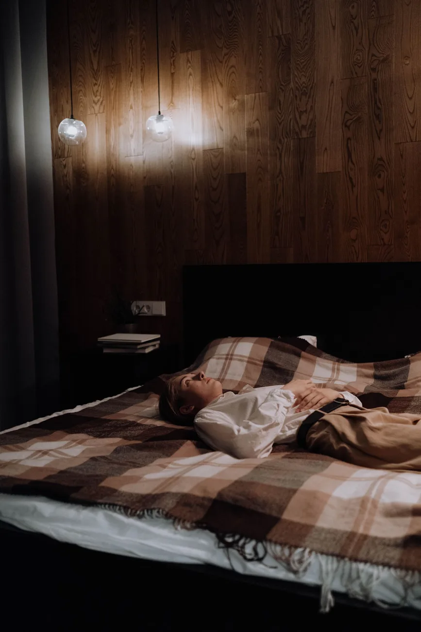 Persona rendida sobre la cama en una habitación tenue