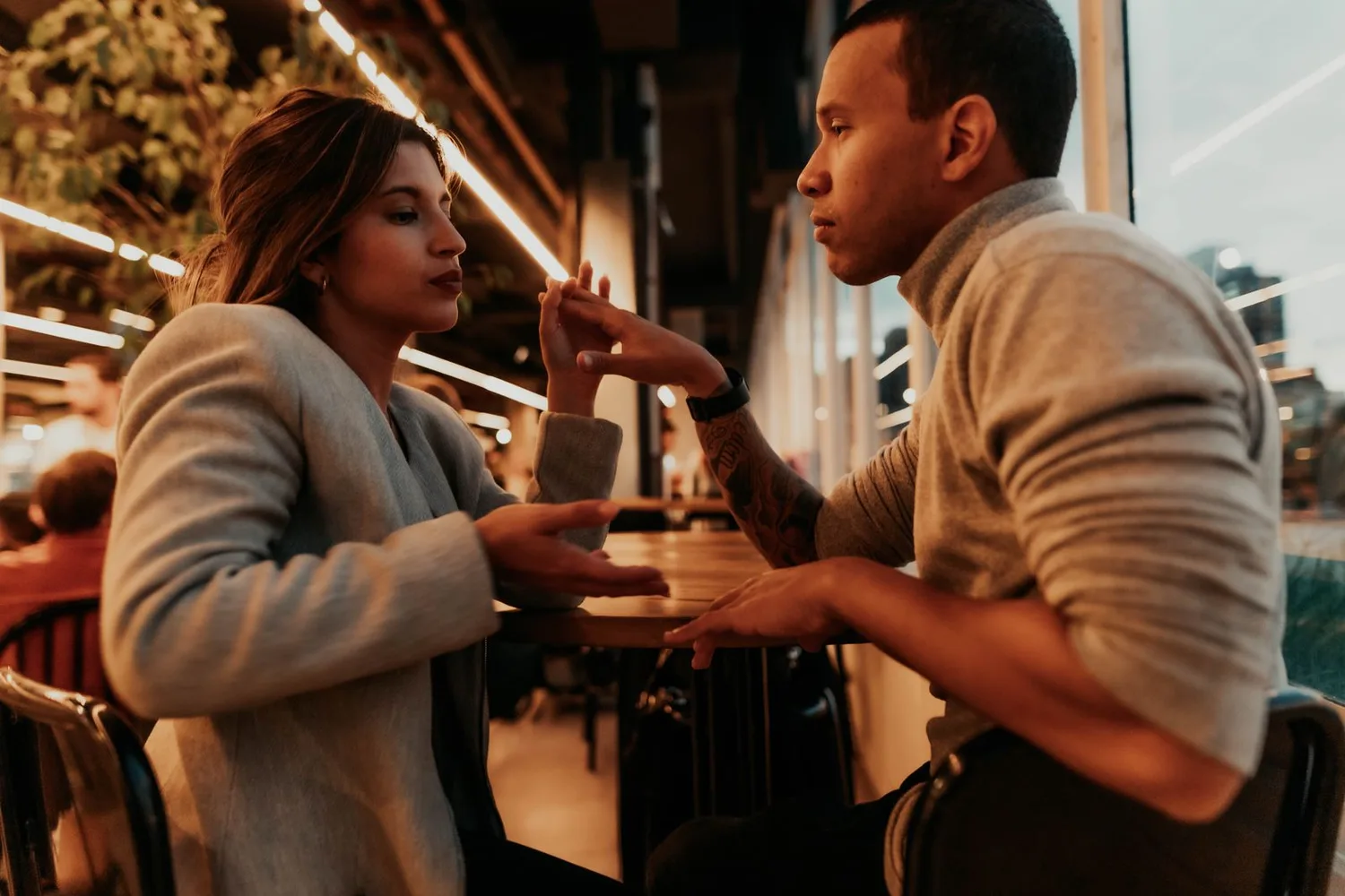 Pareja conversando muy cerca en una cafetería al atardecer