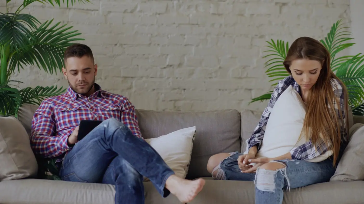 Pareja compartiendo el sofá sin mirarse ni conversar