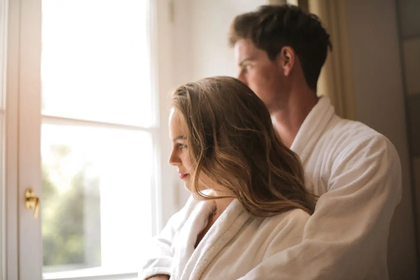 Pareja abrazada junto a una ventana en un momento tranquilo