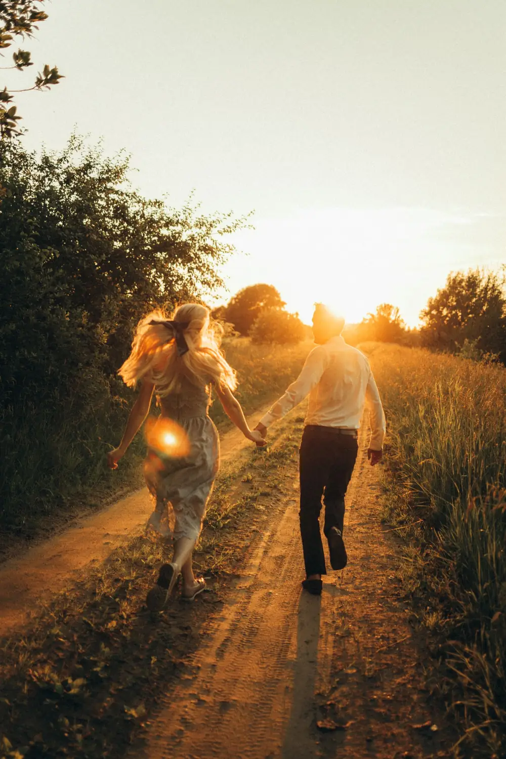 Pareja caminando de la mano por un sendero al atardecer