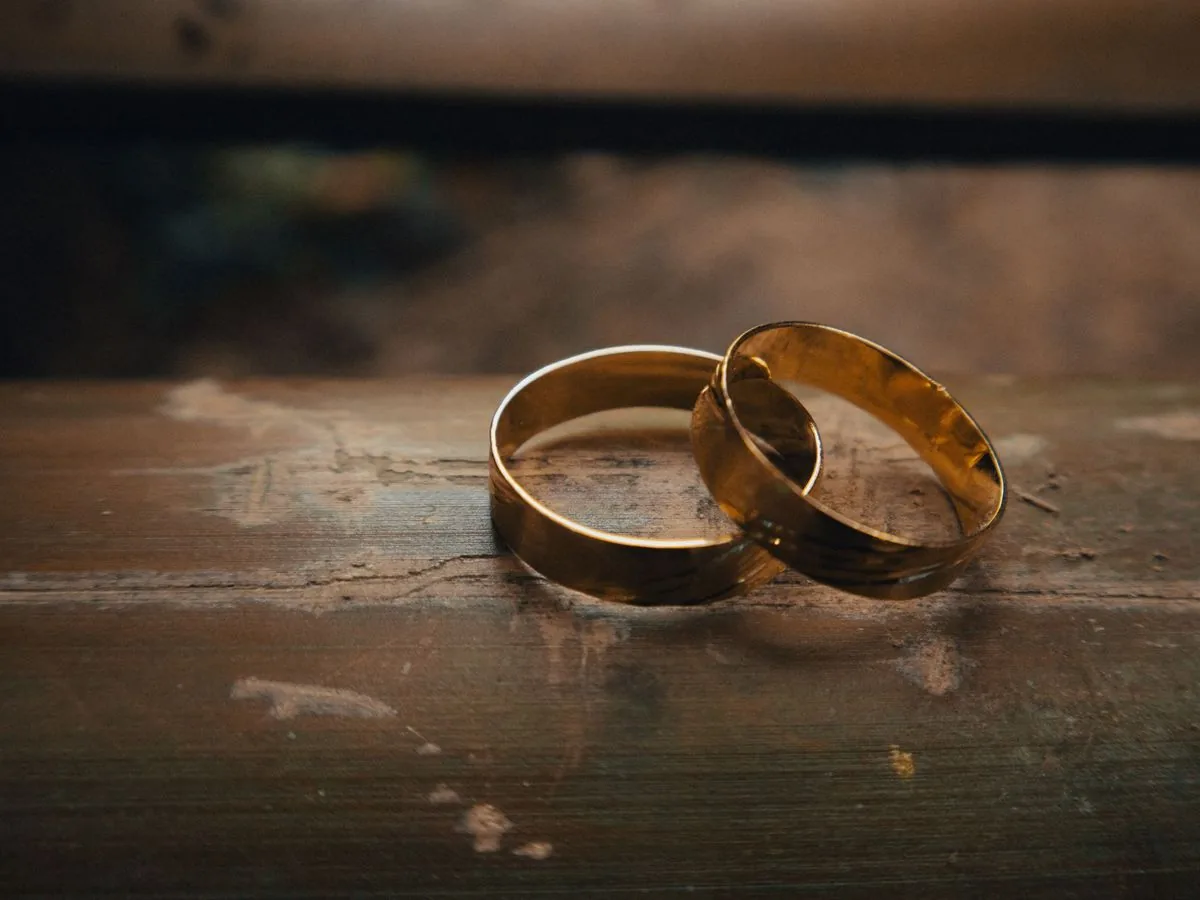 Dos anillos de boda dorados sobre una mesa de madera envejecida