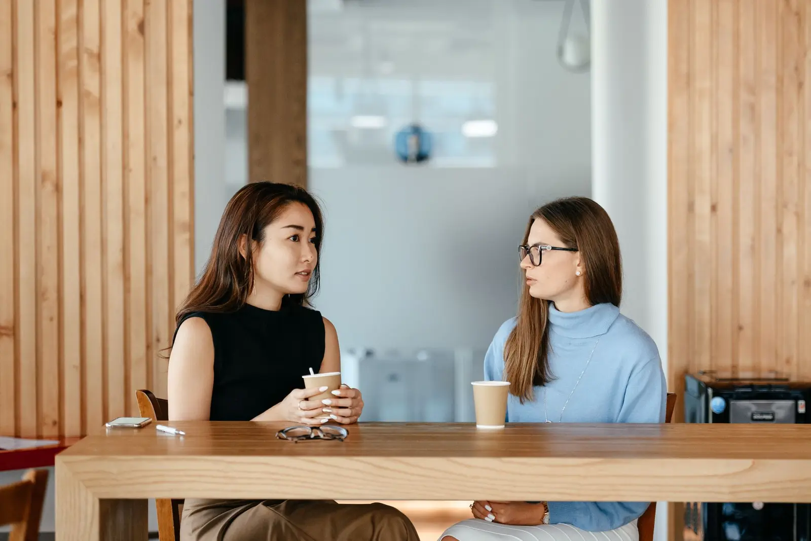 Dos mujeres en una conversación seria y tranquila con café de por medio