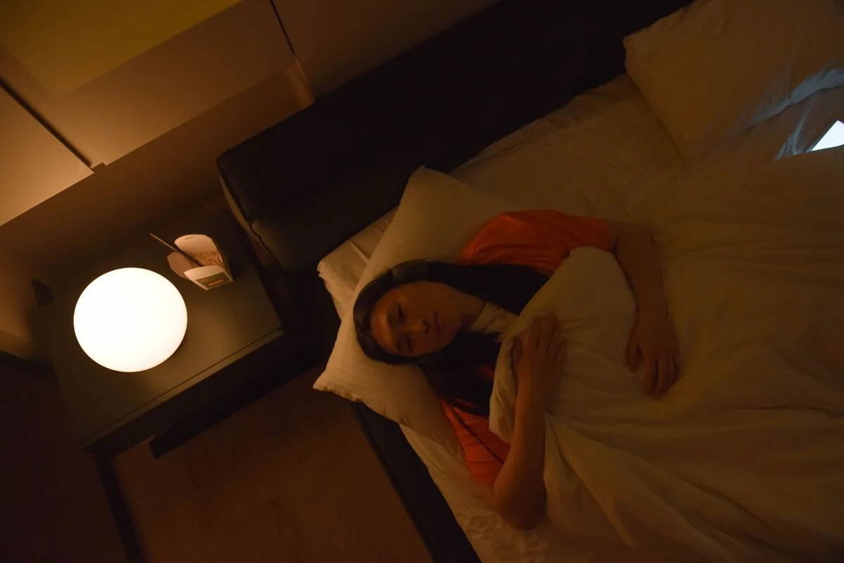Mujer despierta en la cama de noche, iluminada por una lámpara cálida