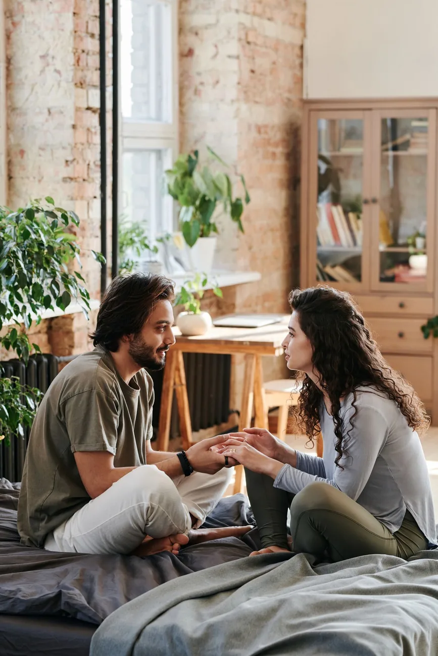 Pareja sentada frente a frente, tomándose de las manos y conversando con calma