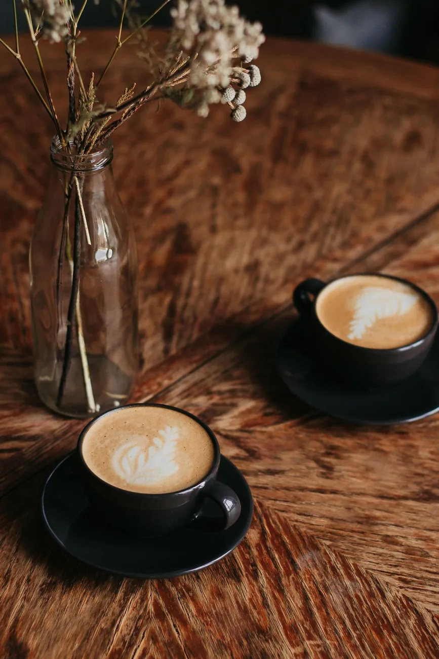 Dos tazas de café juntas sobre una mesa de madera cálida