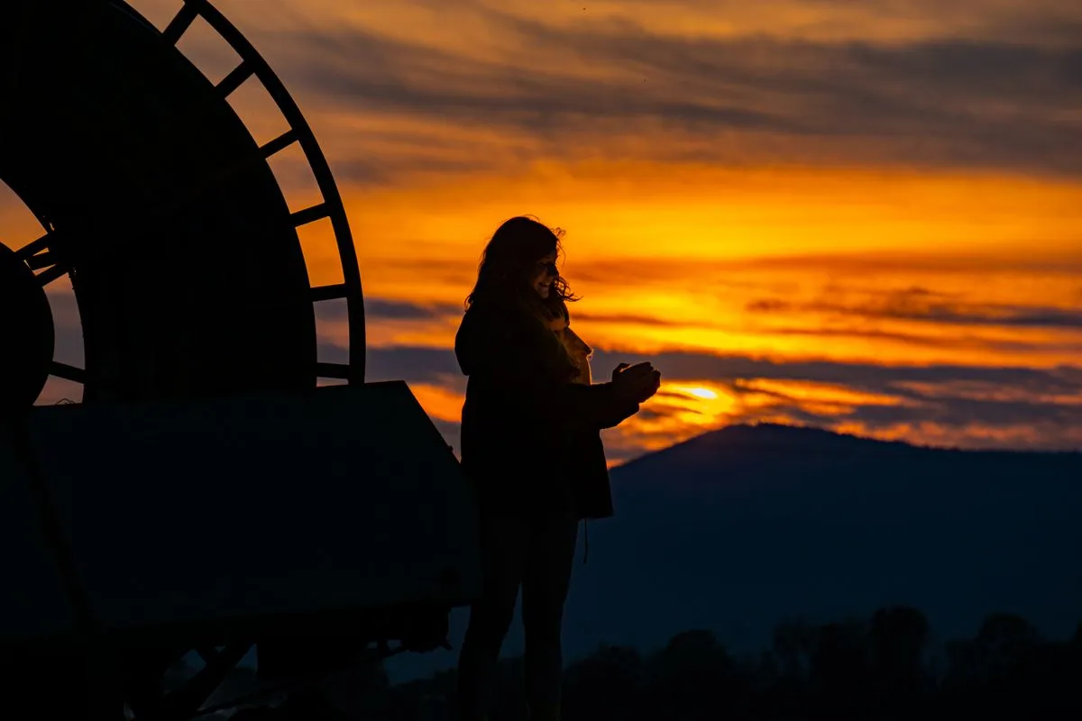Silueta de una mujer en calma frente a un atardecer encendido