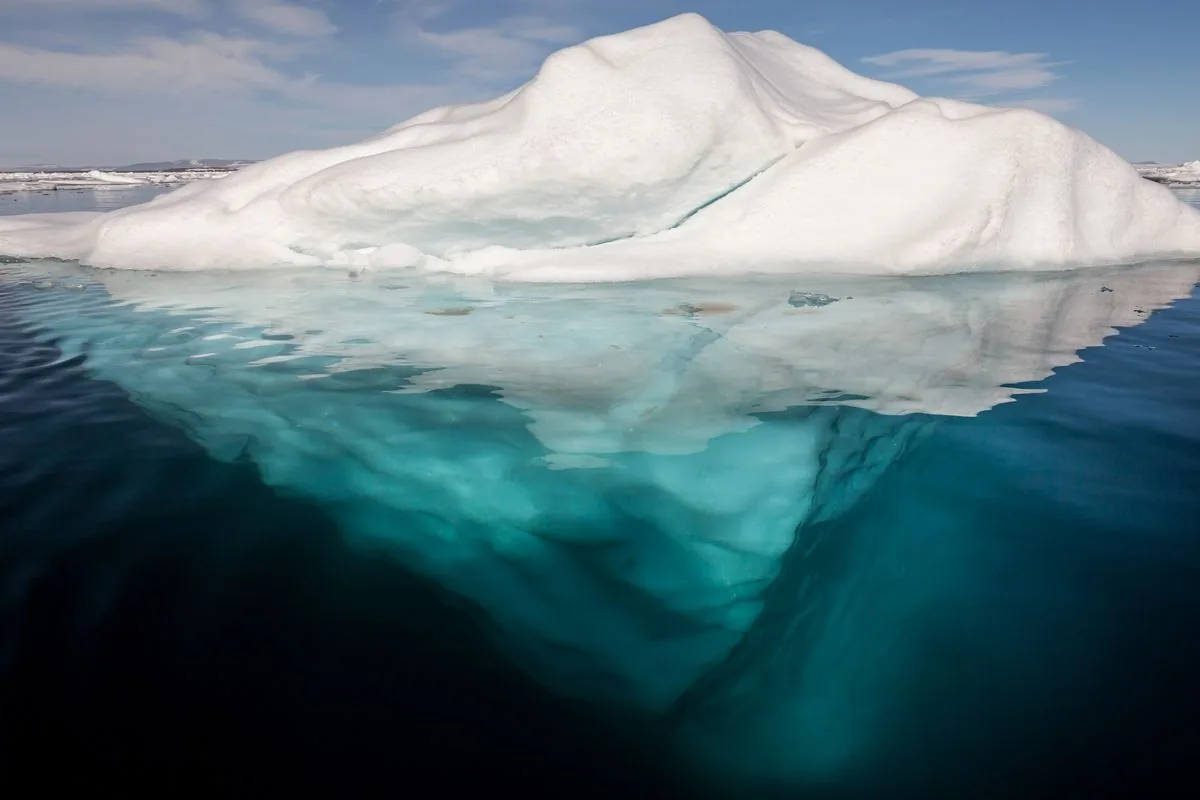 Iceberg en el Ártico: una punta blanca sobre el agua y una masa turquesa mucho más grande bajo la superficie